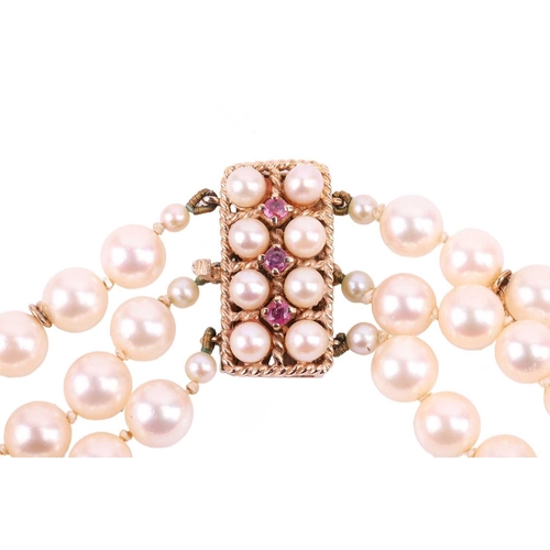 42 - A three-strand pearl choker necklace and matching bracelet, the cultured pearls of cream body colour... 