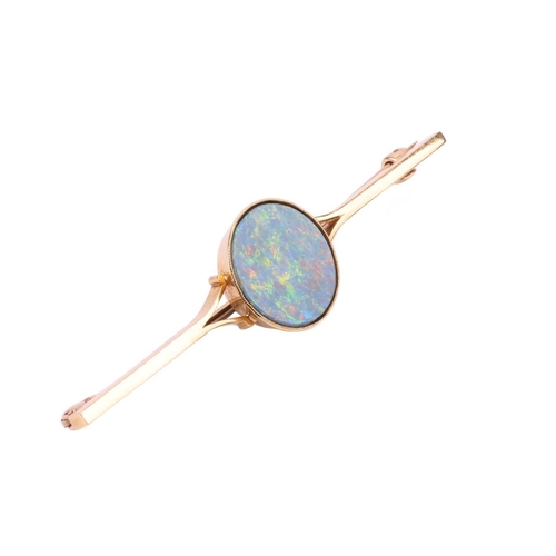 63 - A bar brooch set with a round opal doublet, approximately measures 14.0 mm across, displaying strong... 