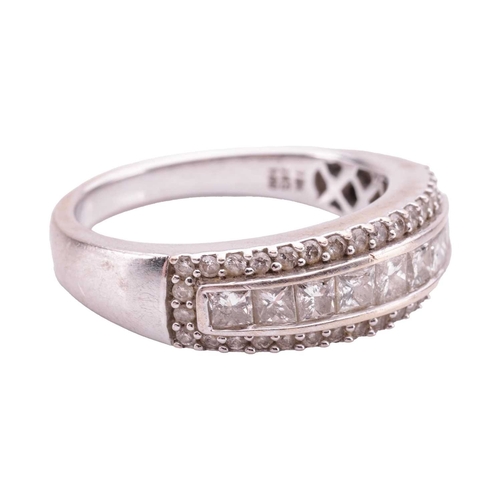 82 - A diamond-set ring, featuring nine princess-cut diamonds, channel-set in a row and surrounded by rou... 