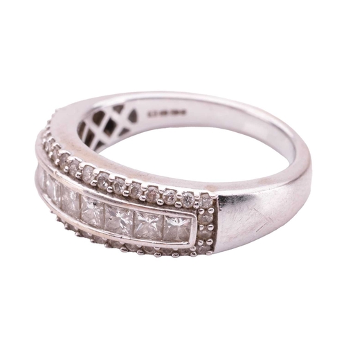 82 - A diamond-set ring, featuring nine princess-cut diamonds, channel-set in a row and surrounded by rou... 