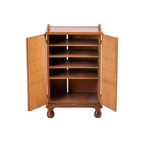 236 - An early 20th-century Cotswold School oak cupboard bookcase with open shelves and solid panel doors ... 