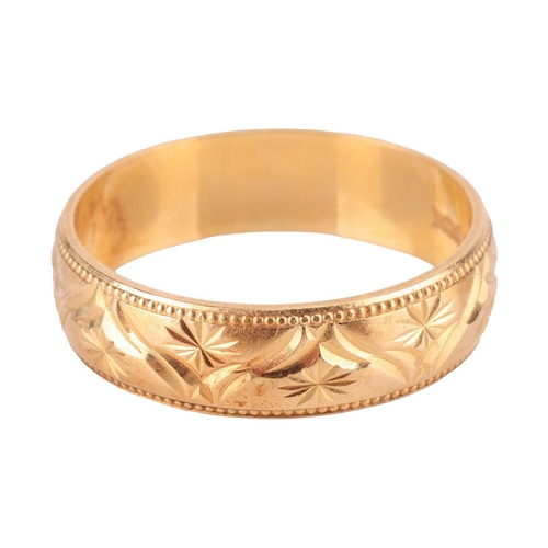 113 - A wedding band in 18ct yellow gold, decorated with bright-cut starbursts design and bordered with gr... 