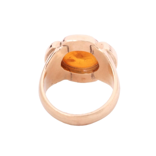 117 - An amber cabochon dress ring, centred with a circular amber cabochon of 11.8 x 5.2 mm, within a styl... 