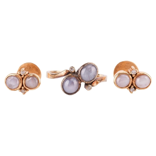 121 - A star sapphire dress ring and a pair of matching earrings; of bypass design, set with two round sta... 