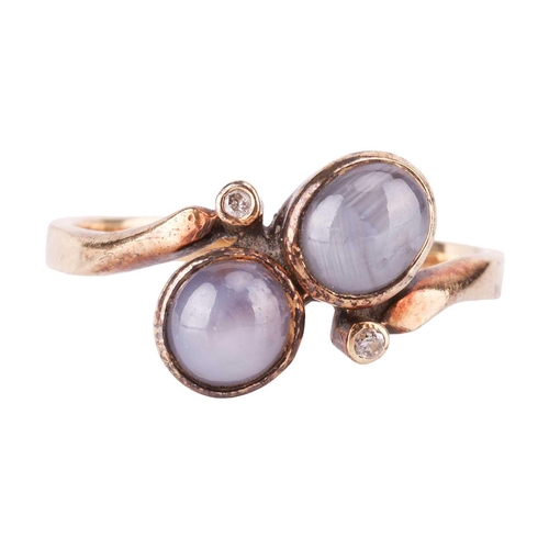 121 - A star sapphire dress ring and a pair of matching earrings; of bypass design, set with two round sta... 