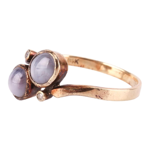 121 - A star sapphire dress ring and a pair of matching earrings; of bypass design, set with two round sta... 