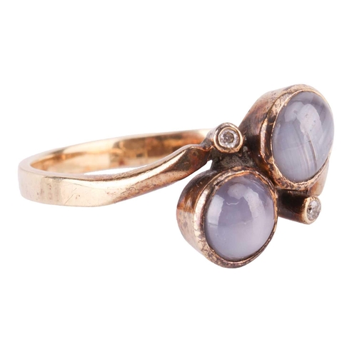 121 - A star sapphire dress ring and a pair of matching earrings; of bypass design, set with two round sta... 