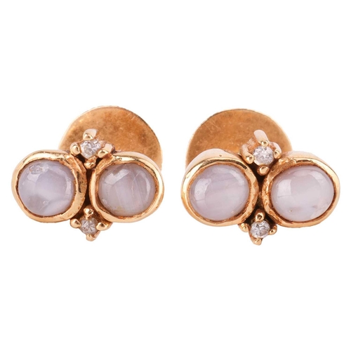 121 - A star sapphire dress ring and a pair of matching earrings; of bypass design, set with two round sta... 