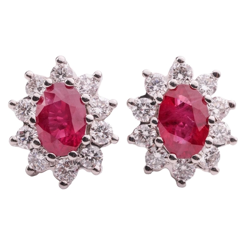 13 - A pair of ruby and diamond cluster earrings, the central oval-cut rubies measuring approximately 6.2... 