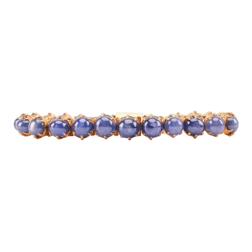 26 - A star sapphire line bracelet, claw-set with twenty-one graduated star sapphires in hinged links, at... 