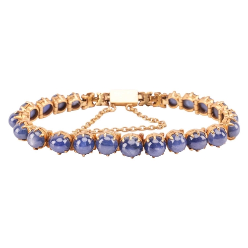 26 - A star sapphire line bracelet, claw-set with twenty-one graduated star sapphires in hinged links, at... 