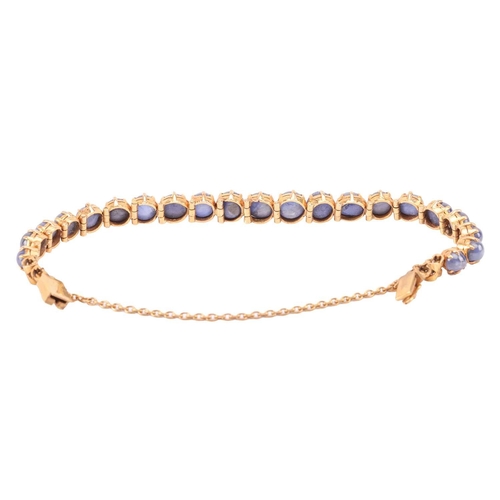 26 - A star sapphire line bracelet, claw-set with twenty-one graduated star sapphires in hinged links, at... 