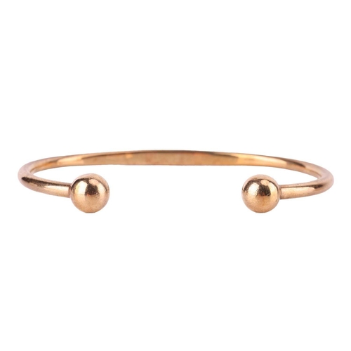 32 - A torque bracelet in 9ct yellow gold, with spherical terminations, struck with Birmingham assay mark... 