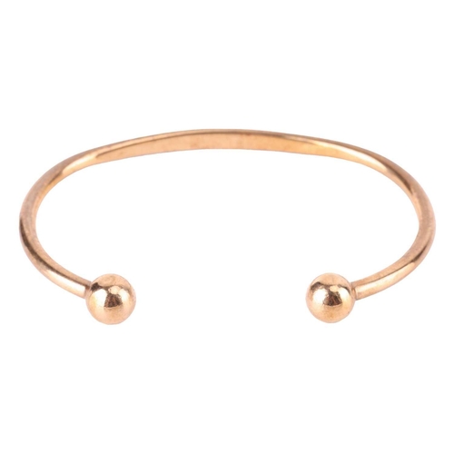 32 - A torque bracelet in 9ct yellow gold, with spherical terminations, struck with Birmingham assay mark... 