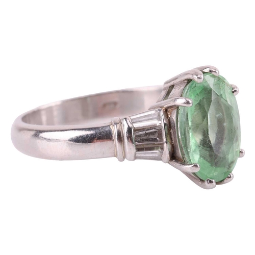 37 - A tourmaline and diamond dress ring, centred with a pale apple green oval-cut tourmaline of 10.7 x 7... 