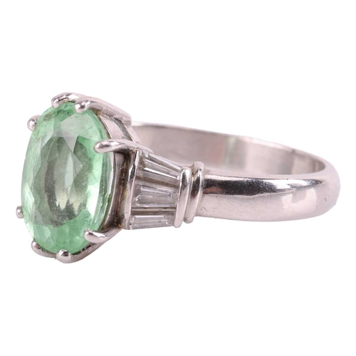 37 - A tourmaline and diamond dress ring, centred with a pale apple green oval-cut tourmaline of 10.7 x 7... 