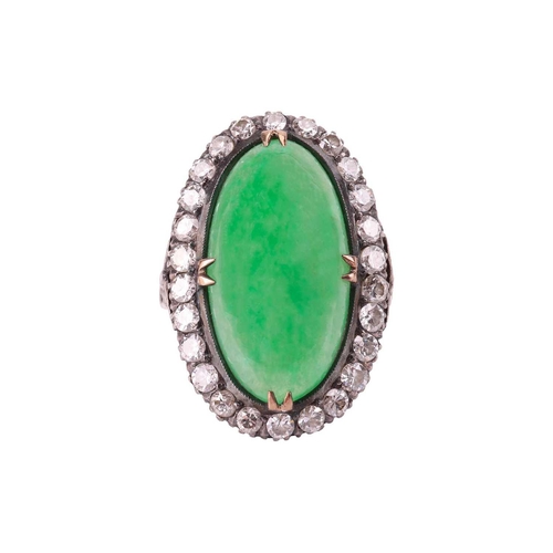 44 - A jade and diamond halo ring, featuring an elongated oval jadeite cabochon of yellowish-green colour... 