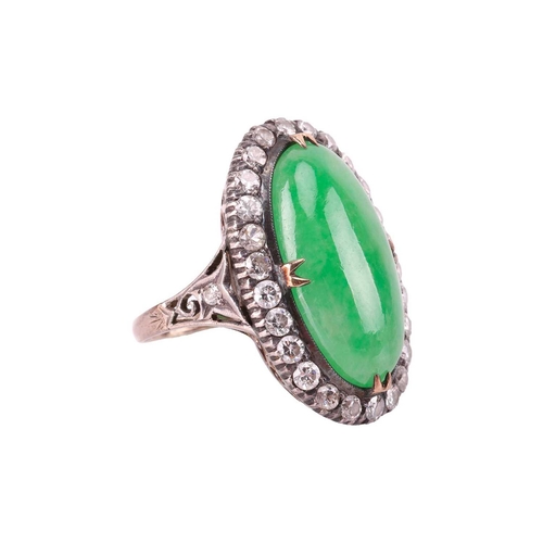 44 - A jade and diamond halo ring, featuring an elongated oval jadeite cabochon of yellowish-green colour... 