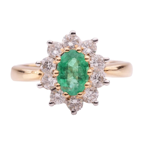 46 - An emerald and diamond cluster ring in 18ct yellow gold, centred with an oval-cut emerald of 6.9 x 5... 