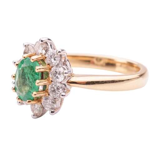 46 - An emerald and diamond cluster ring in 18ct yellow gold, centred with an oval-cut emerald of 6.9 x 5... 