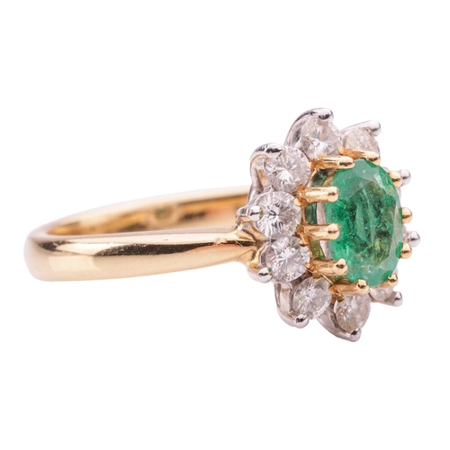 46 - An emerald and diamond cluster ring in 18ct yellow gold, centred with an oval-cut emerald of 6.9 x 5... 