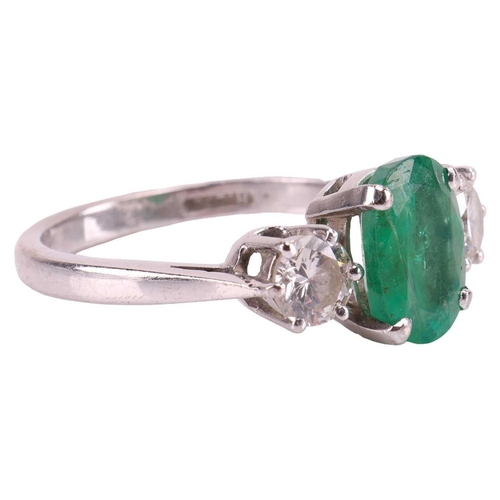 63 - An emerald and diamond three-stone ring in 18ct white gold, centred with an oval-cut emerald of 9.3 ... 