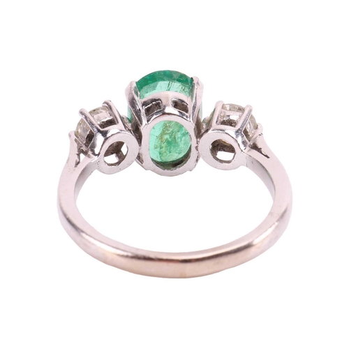 63 - An emerald and diamond three-stone ring in 18ct white gold, centred with an oval-cut emerald of 9.3 ... 