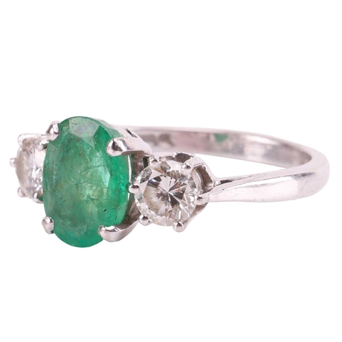 63 - An emerald and diamond three-stone ring in 18ct white gold, centred with an oval-cut emerald of 9.3 ... 