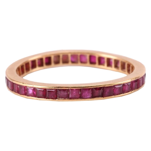 8 - A ruby-set eternity ring, channel-set with calibre-cut rubies, to an unmarked yellow metal mount tes... 