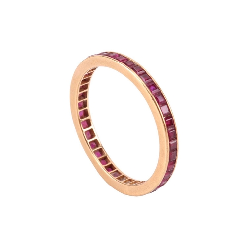 8 - A ruby-set eternity ring, channel-set with calibre-cut rubies, to an unmarked yellow metal mount tes... 