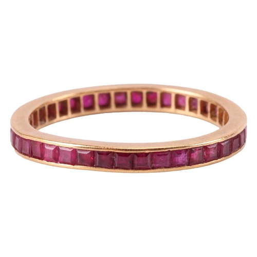 8 - A ruby-set eternity ring, channel-set with calibre-cut rubies, to an unmarked yellow metal mount tes... 