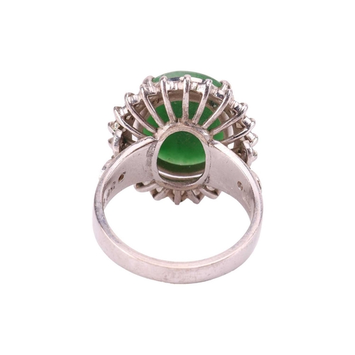 94 - A jade and diamond halo ring, comprising an oval jadeite cabochon of deep green colour, approximatel... 