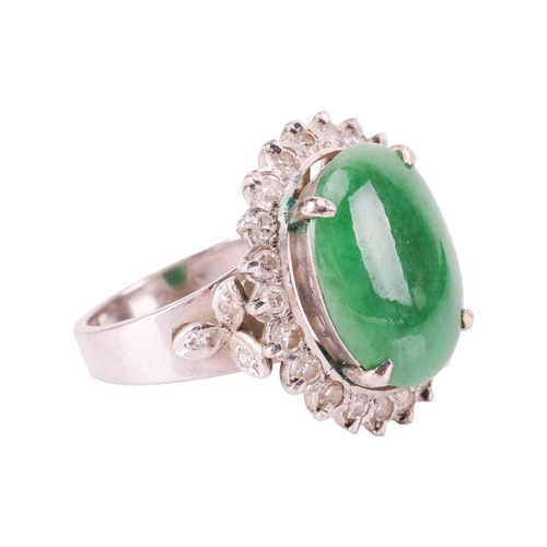 94 - A jade and diamond halo ring, comprising an oval jadeite cabochon of deep green colour, approximatel... 