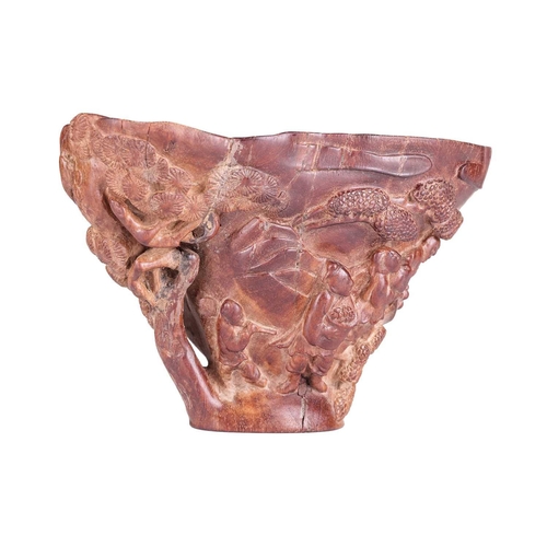 71 - A Chinese hardwood libation cup, carved to resemble a rhinoceros horn, the body decorated in relief ... 