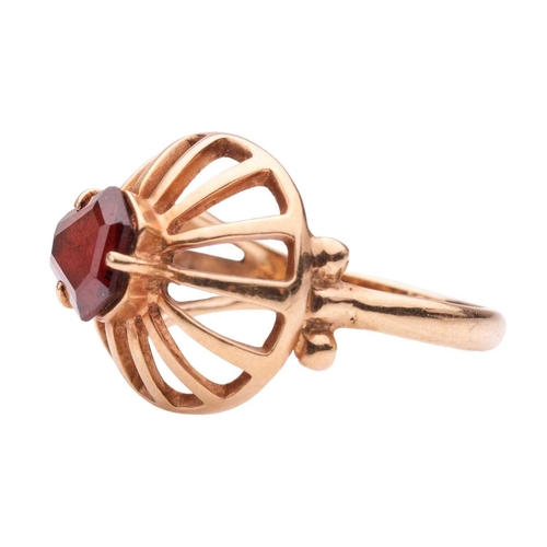 108 - A garnet-set dress ring, set with a shield-shaped step-cut garnet in collet, to a domed wire ring he... 