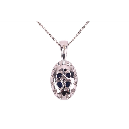 140 - A sapphire and diamond-set cluster pendant, the 18ct white gold oval mount featuring twelve round sa... 