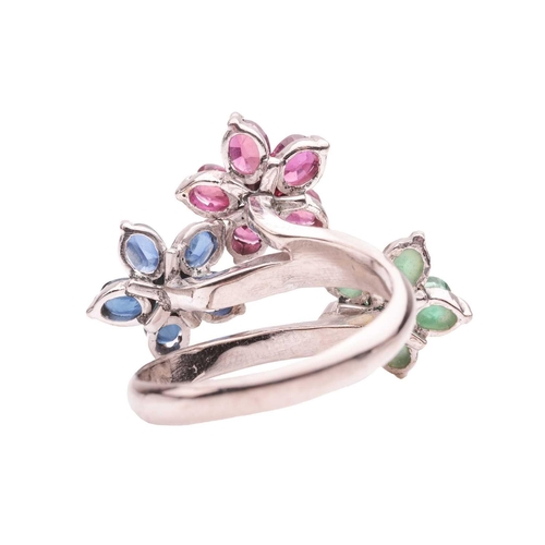 167 - A floral gem-set crossover ring, featuring three staggered flower heads, each set with a round brill... 