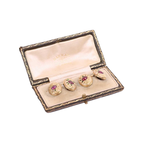 2 - A pair of Edwardian ruby-set enamel cufflinks, each oval panel centred with an oval ruby cabochon, e... 