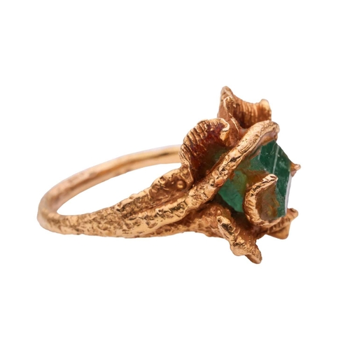 220 - A Modernist dress ring set with a synthetic emerald crystal, to an abstract flowerhead mount leading... 