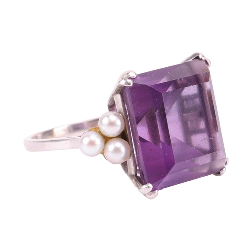 239 - An amethyst and seed pearl dress ring, featuring a step-cut amethyst of 14.0 x 13.2 mm, flanked by t... 