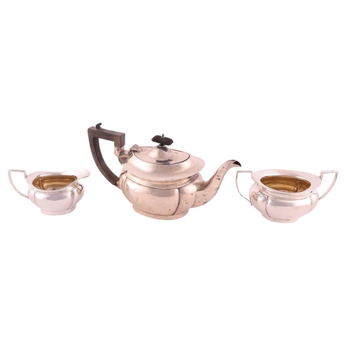 331 - A three piece silver teaset, of panelled oval form, the teapot with angled fruitwood handle and flut... 