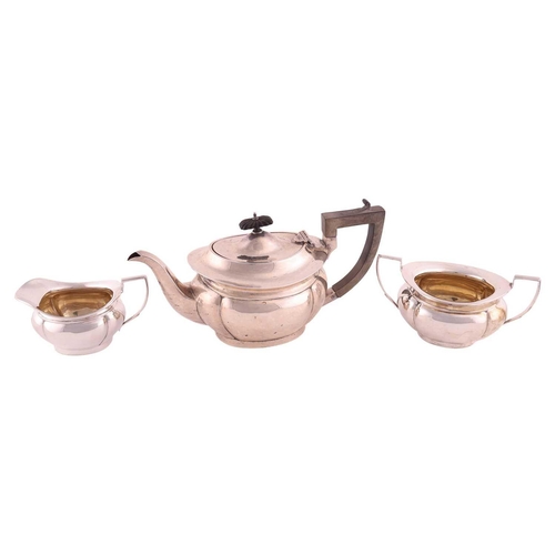 331 - A three piece silver teaset, of panelled oval form, the teapot with angled fruitwood handle and flut... 