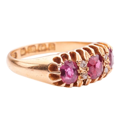 40 - A ruby three-stone ring, claw-set with three slightly graduated oval-cut rubies, interspersed by duo... 