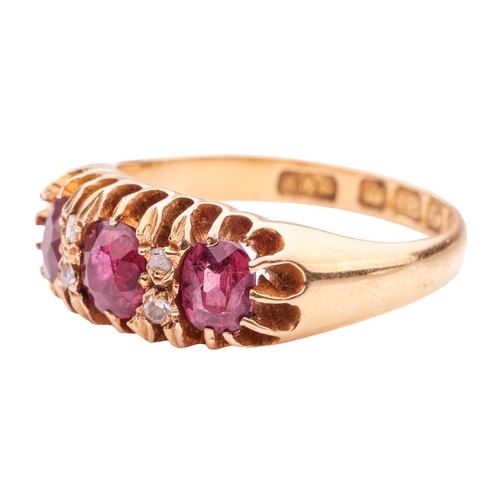 40 - A ruby three-stone ring, claw-set with three slightly graduated oval-cut rubies, interspersed by duo... 