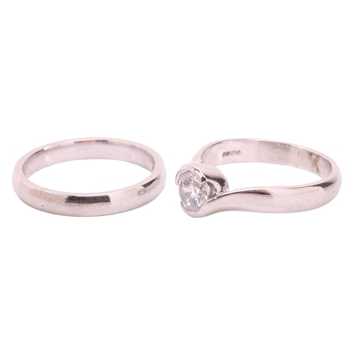 43 - A diamond solitaire ring and matching wedding band, the solitaire ring featuring a round brilliant d... 