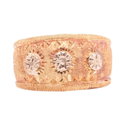 62 - A dress ring of tapered and textured design, overlaid to the front with three starbursts, between re... 