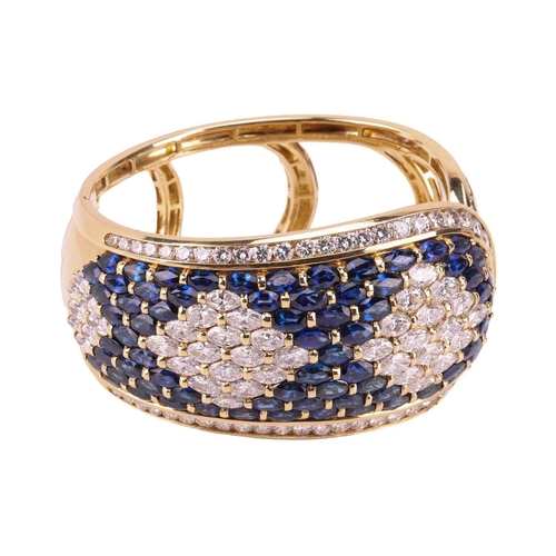 79 - A sapphire and diamond-hinged bangle the tapered plaque decorated throughout with oval-cut sapphires... 