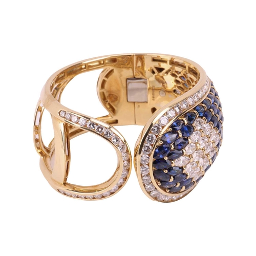 79 - A sapphire and diamond-hinged bangle the tapered plaque decorated throughout with oval-cut sapphires... 