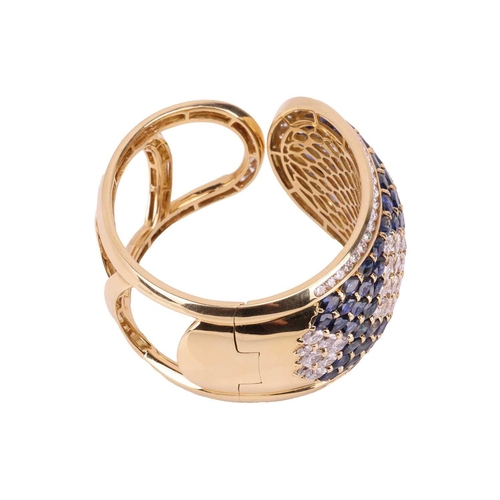 79 - A sapphire and diamond-hinged bangle the tapered plaque decorated throughout with oval-cut sapphires... 