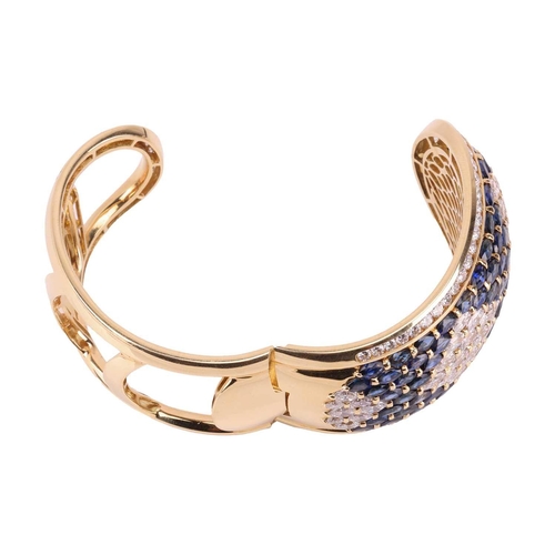 79 - A sapphire and diamond-hinged bangle the tapered plaque decorated throughout with oval-cut sapphires... 